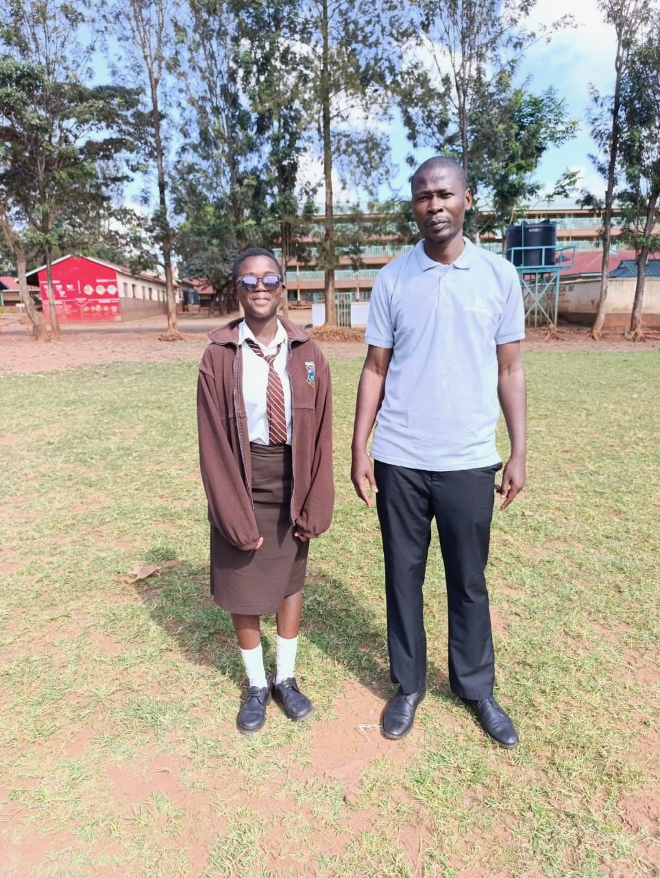 A secondary school student in her brown school uniform with her Soma Initiative coordinator