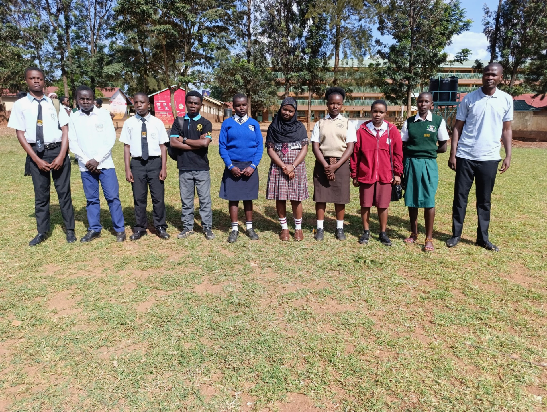 Soma Initiative scholarship students in their school uniforms, standing together with their programme coordinator on the school field