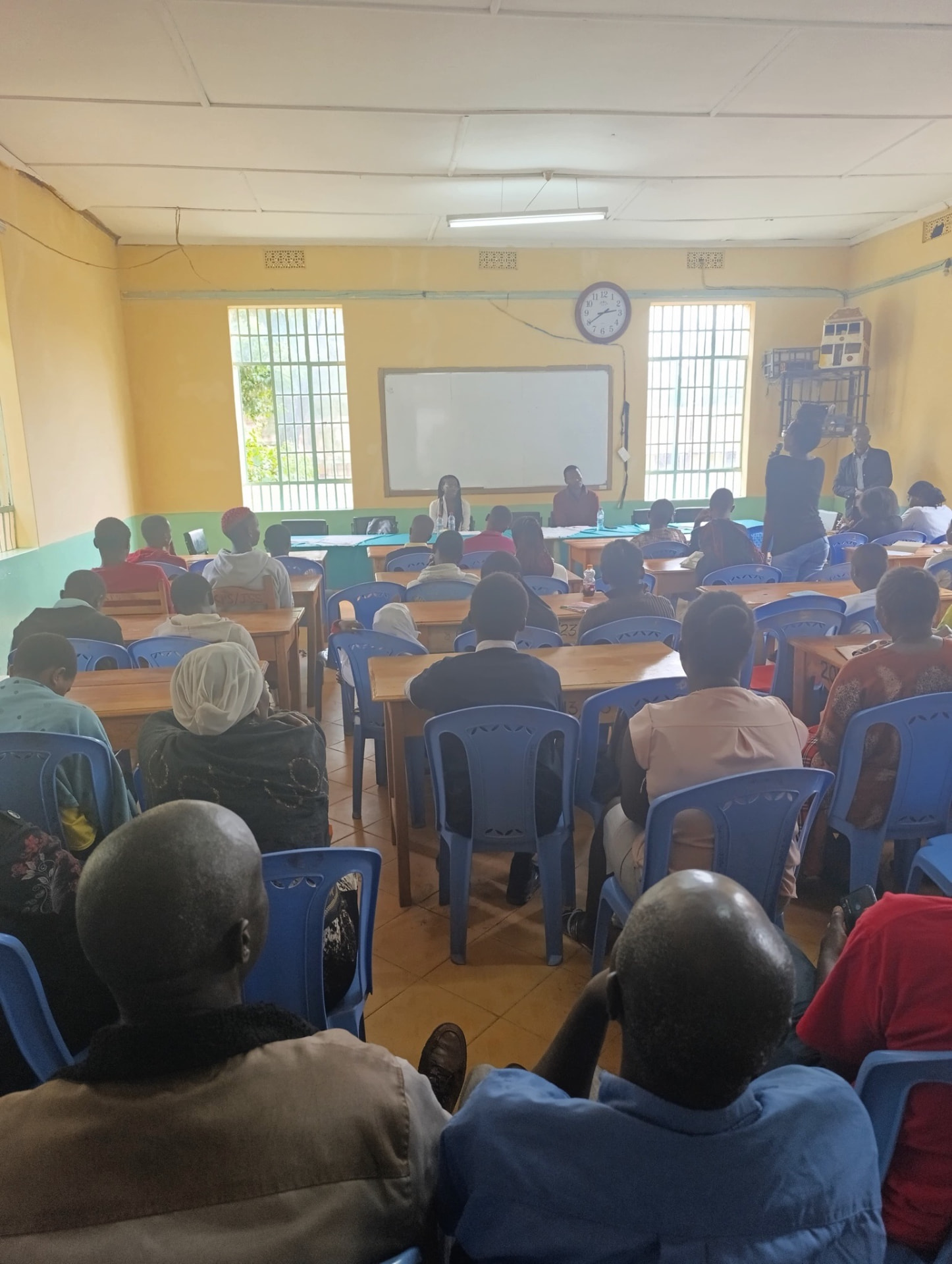 Parents, students and teachers gathered in a classroom for a Soma Initiative community meeting